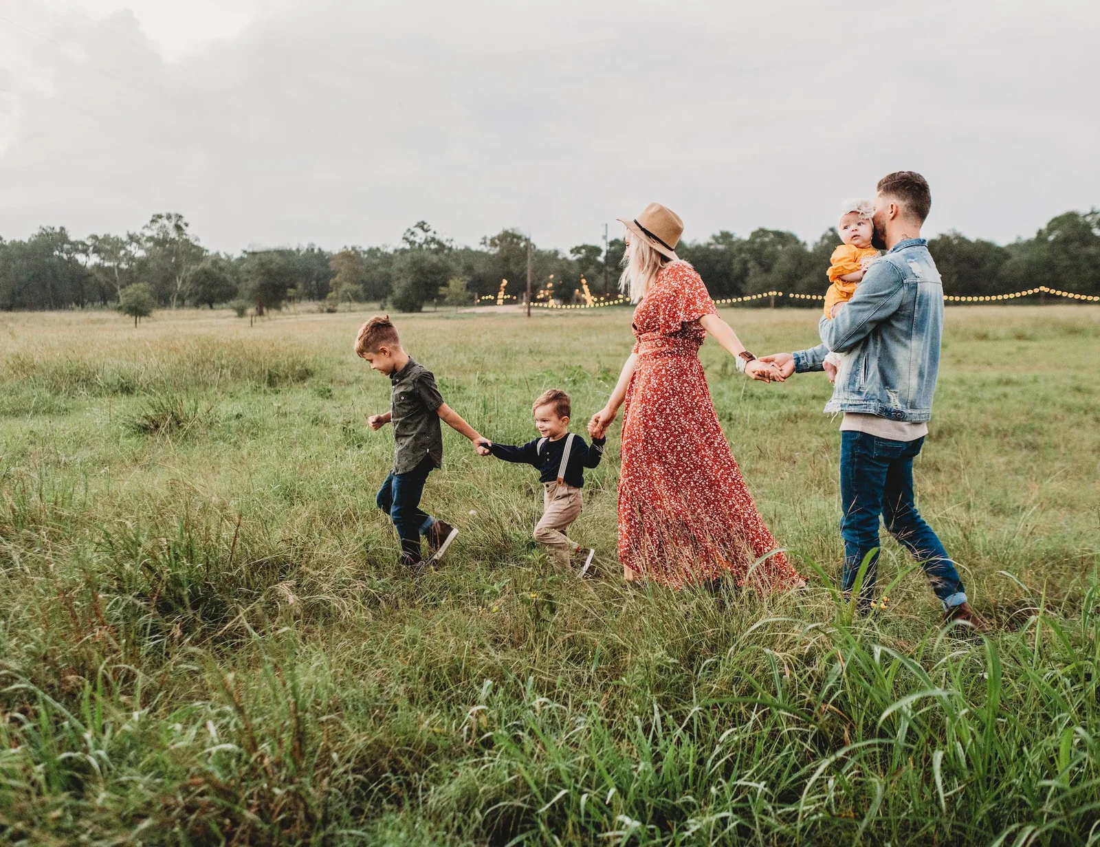 Parents walking through a field with their children.